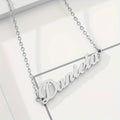 Silver personalized nameplate necklace on tile background